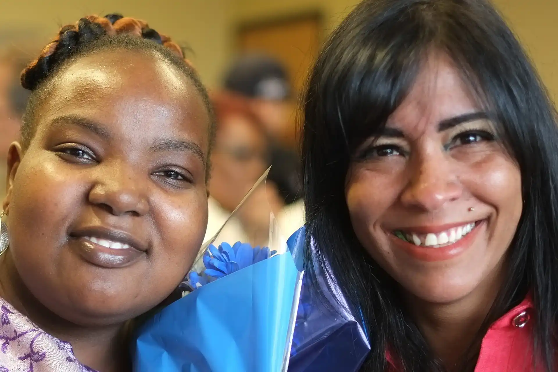 Two graduates at the Clemente Worcester graduation, one holding flowers.