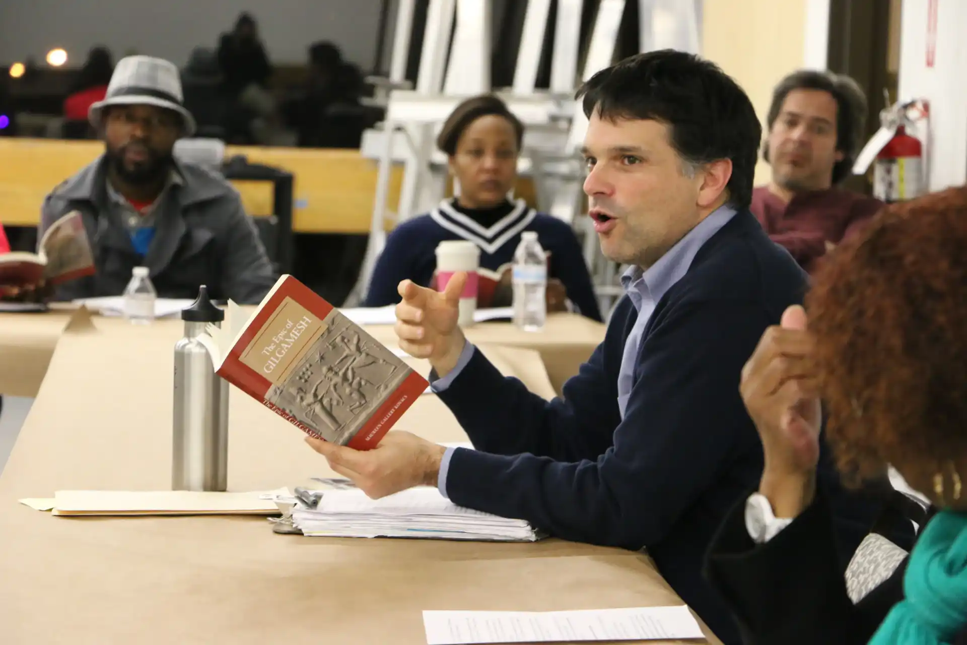 A faculty member holds up The Epic of Gilgamesh during seminar.
